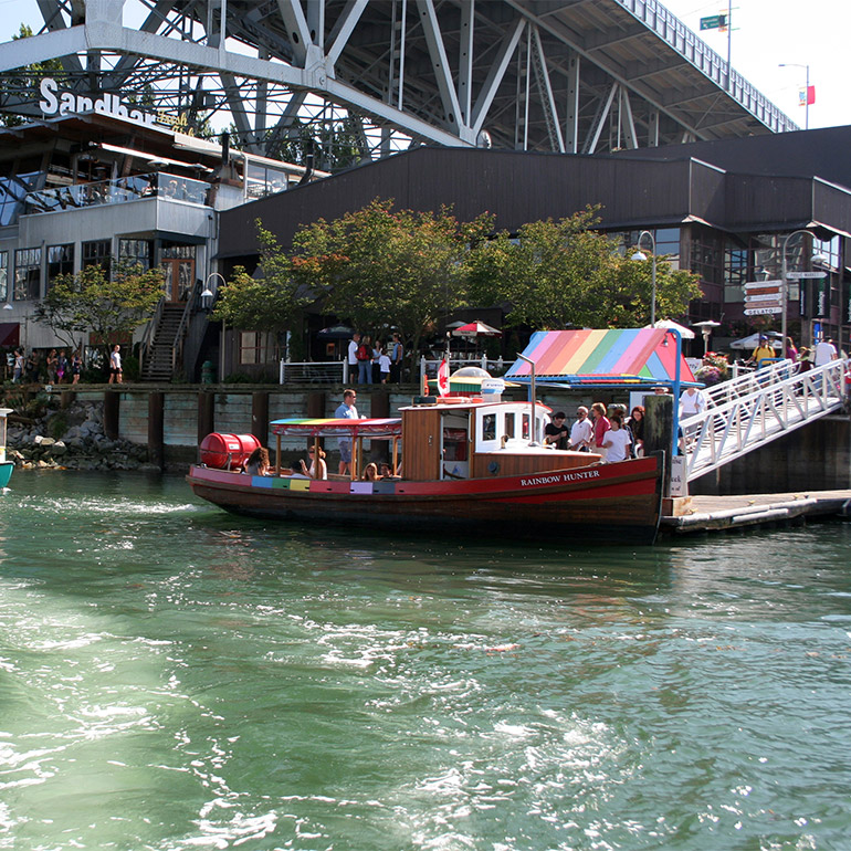 a group of people set out on a water taxi called the rainbow hunter, a wooden boat about 40 feet long with a small cabin and awning